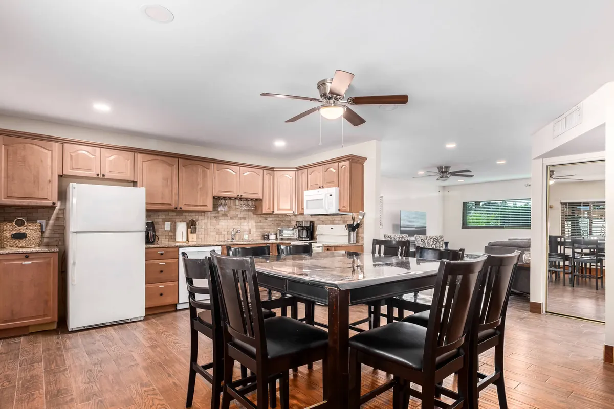 A spacious kitchen island sits at the heart of the open layout, surrounded by wood cabinetry and modern appliances. The view includes the adjacent dining area, making it easy to imagine moving seamlessly between cooking, dining, and relaxing.