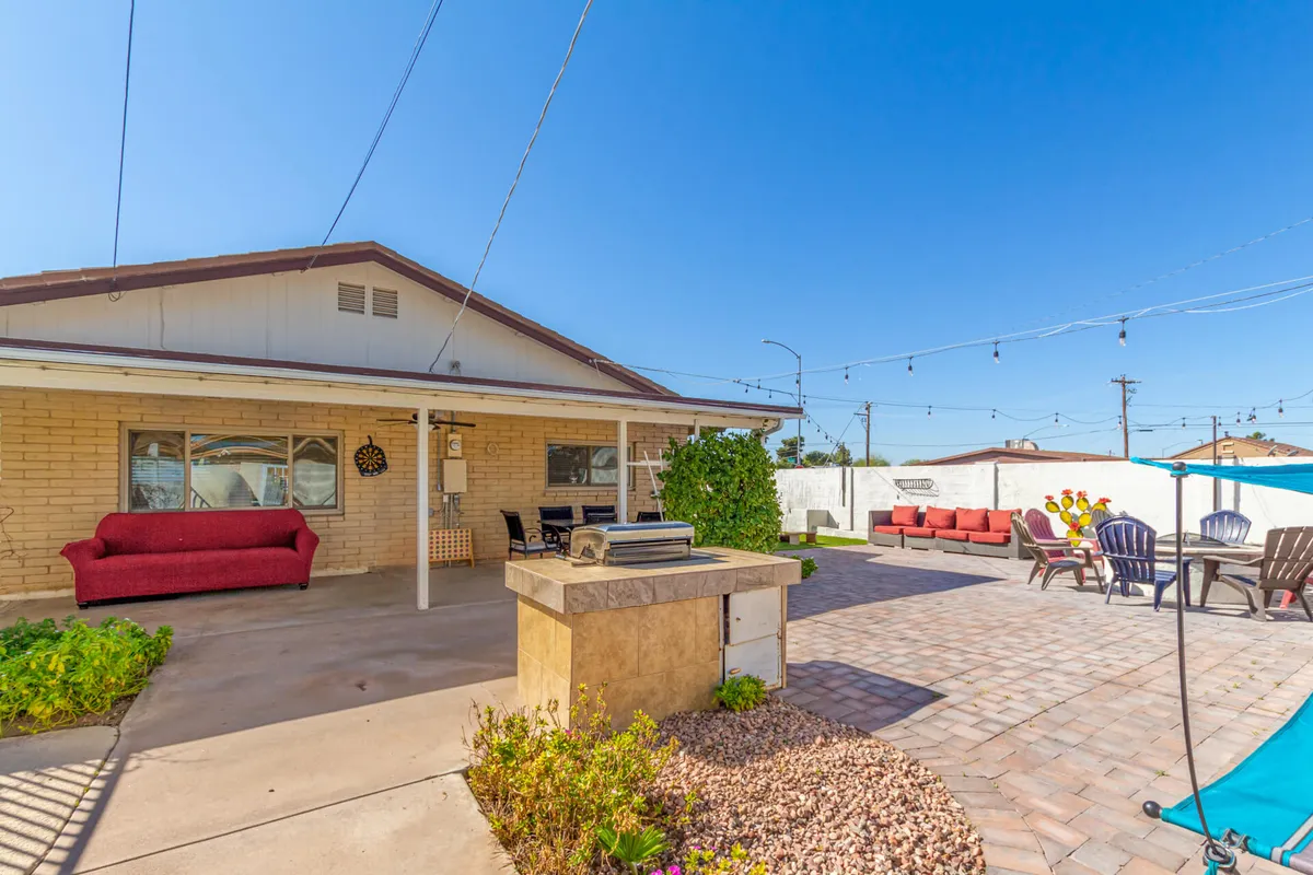 A colorful exterior patio scene with a grill, ample seating, and bright outdoor lighting. Cheerful chairs and festive decor set the atmosphere for outdoor dining, casual gatherings, and group celebrations.