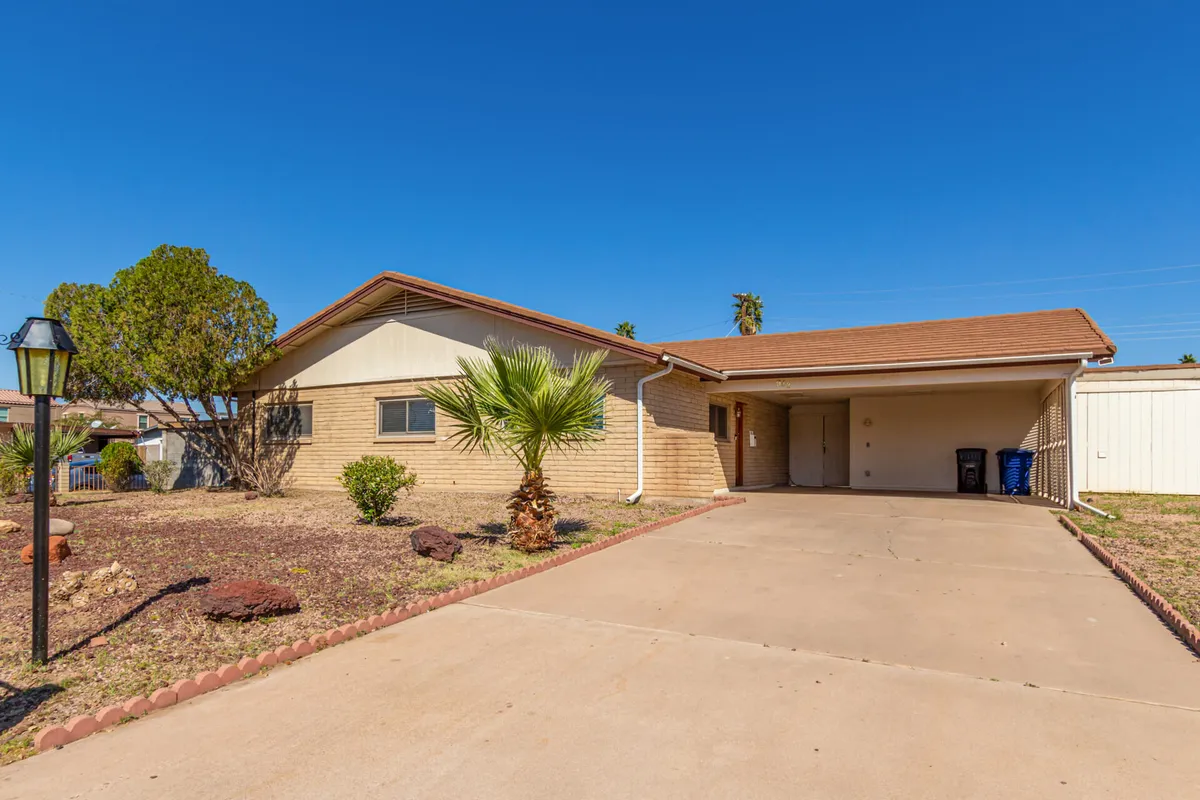 A wide view of the home’s exterior and landscaped front yard, with a palm tree, brick facade, driveway, and carport. The scene feels warm and welcoming, setting the stage for neighborhood exploration and family comings and goings.